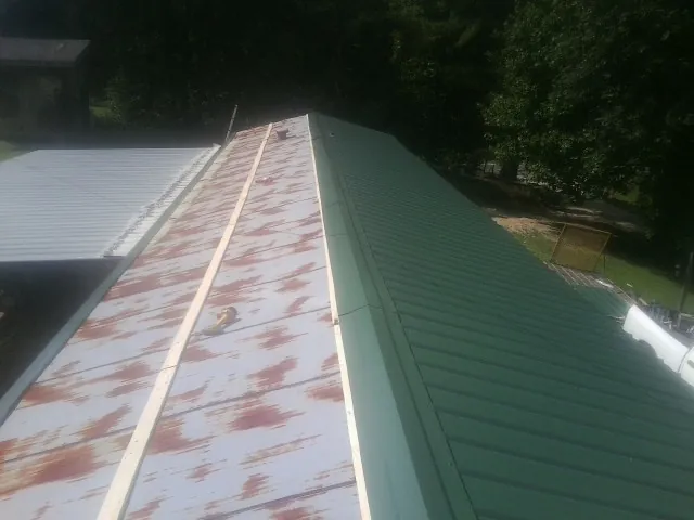 Old rusted panels beside newly installed green metal roofing — Wind Damage Roof Repair by Roofing Brothers in Brookside