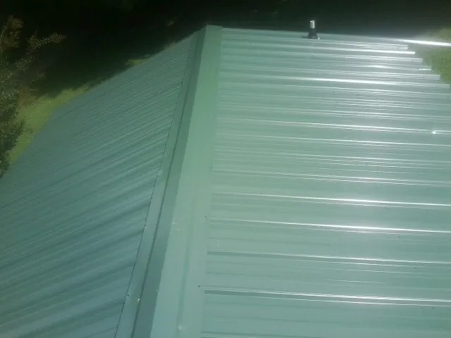 New green metal panels meeting at the ridge of a roof — Flat Roof Repair work by our crew in Brookside