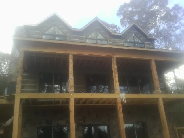 Dormers and porch framing on a large log home under construction — Roof Coating work by our crew in Brookside