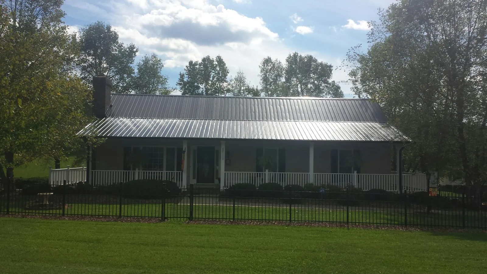 Gray metal roof on a brick ranch with a full width front porch — Gutter Guard Installation work by our crew in Brookside