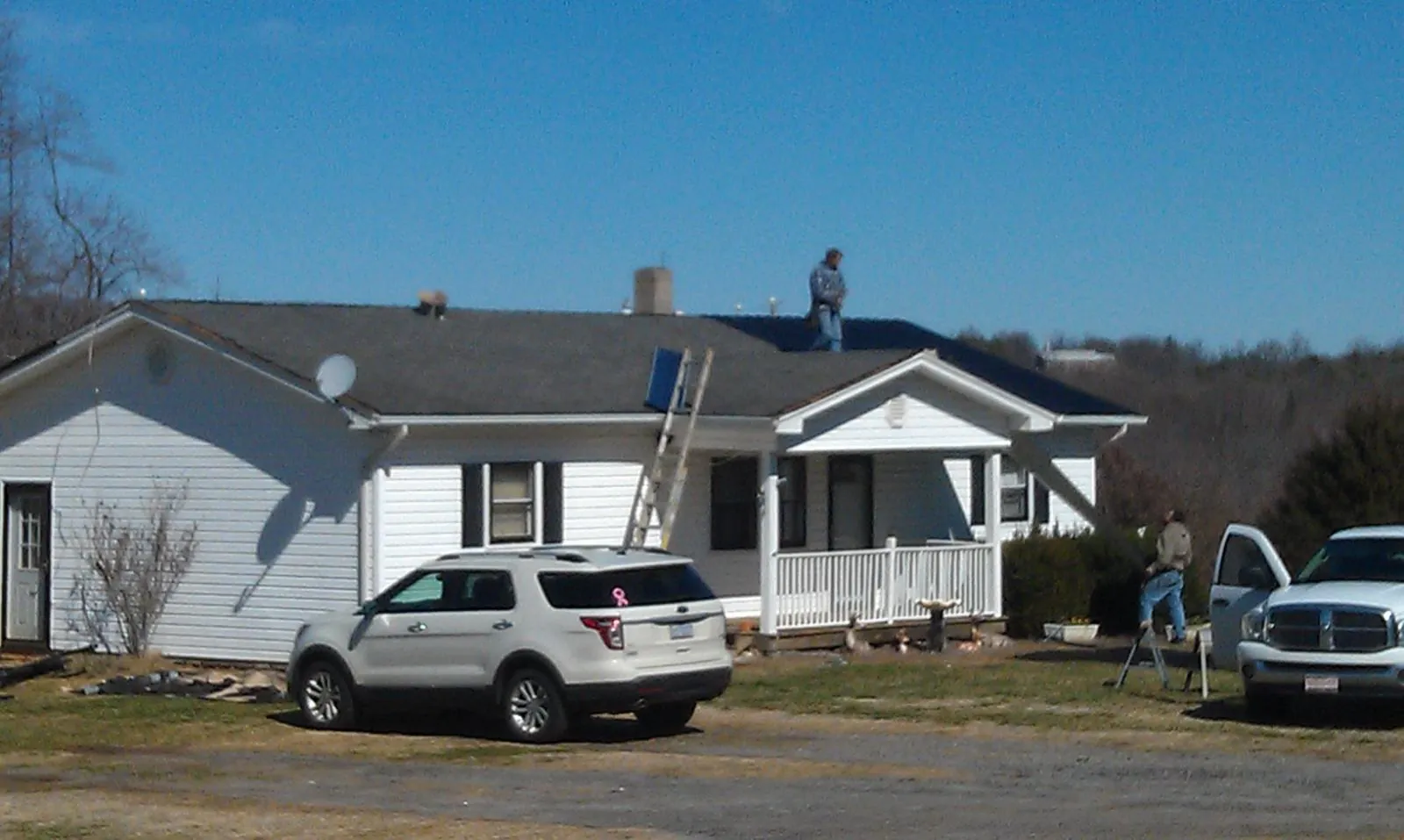 Roofers stripping shingles from a white ranch house roof in Brookside